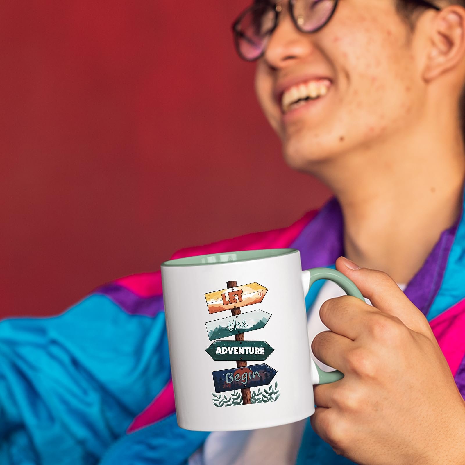 71d3eepdmtl.jpg Smiling person in a colourful jacket holding the Let the Adventure Begin mug with a light green handle