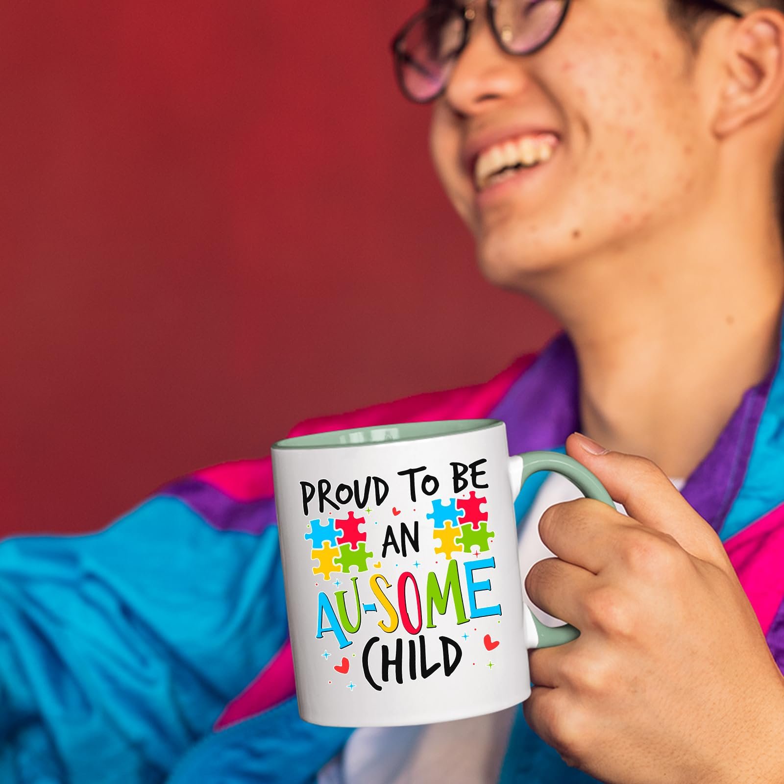 71gynj4r7kl.jpg Smiling person in a colourful jacket holding the Proud to Be an Au-Some Child mug with a light green handle