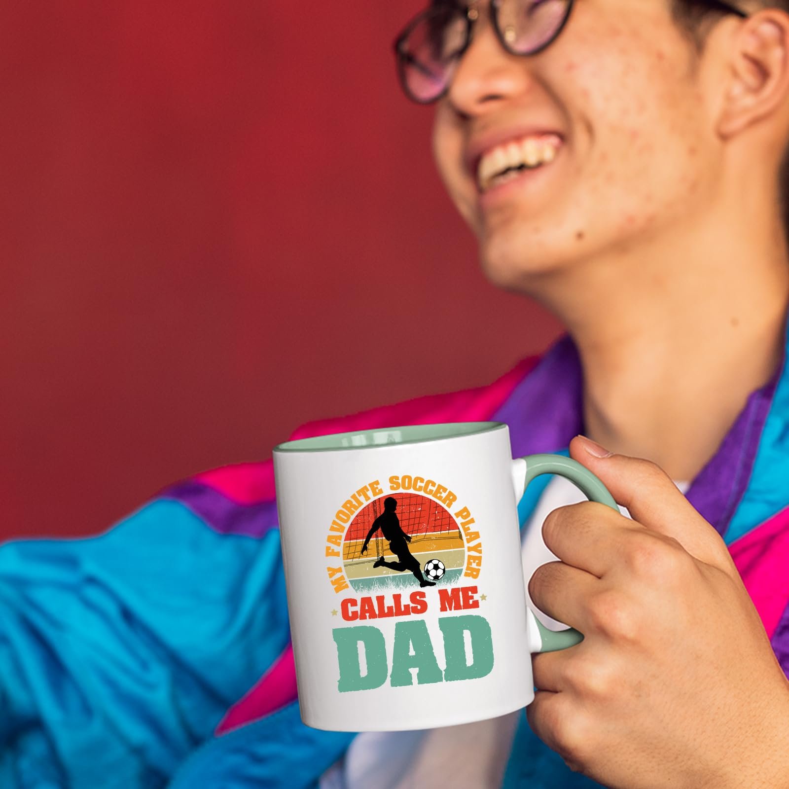 71qzcy6z5wl.jpg Smiling person in a colourful jacket holding the Soccer Dad mug with a light green handle