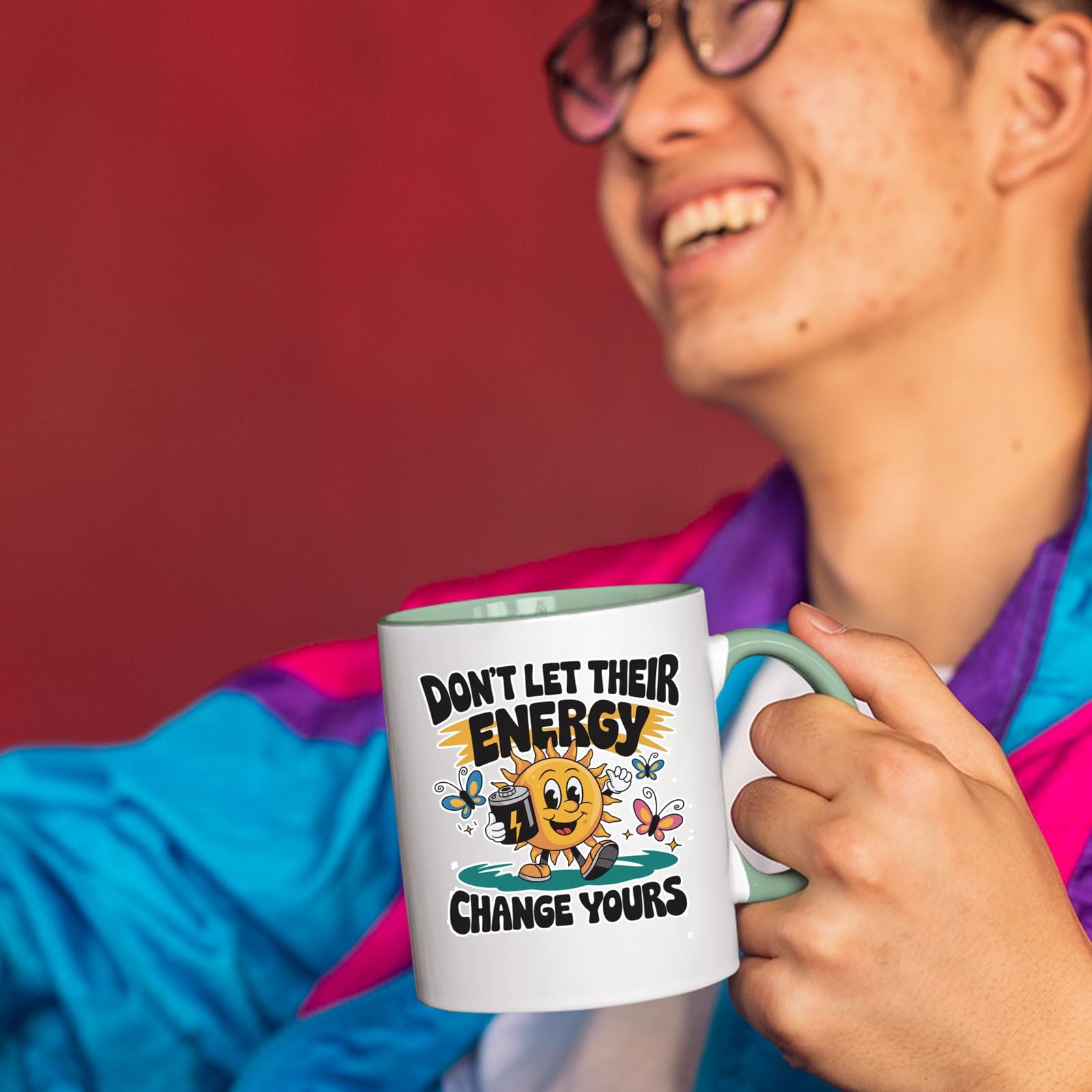 71x3pcor kl.jpg Smiling person in a colourful jacket holding the Positive Vibes sun mug with a light green handle