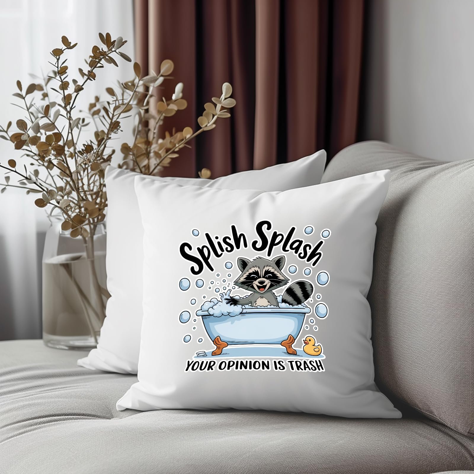 81kfkysqaql.jpg Splish Splash raccoon cushion on a grey sofa beside dried flowers